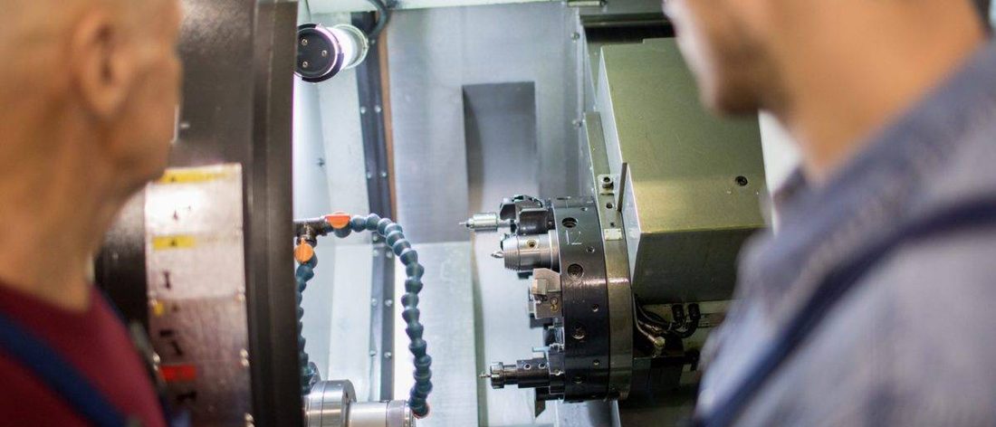 Dos técnicos junto a un torno CNC durante una reparación
