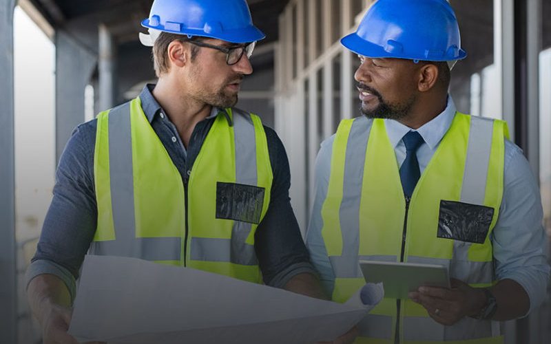 Dos ingenieros con casco revisando planos de una instalación