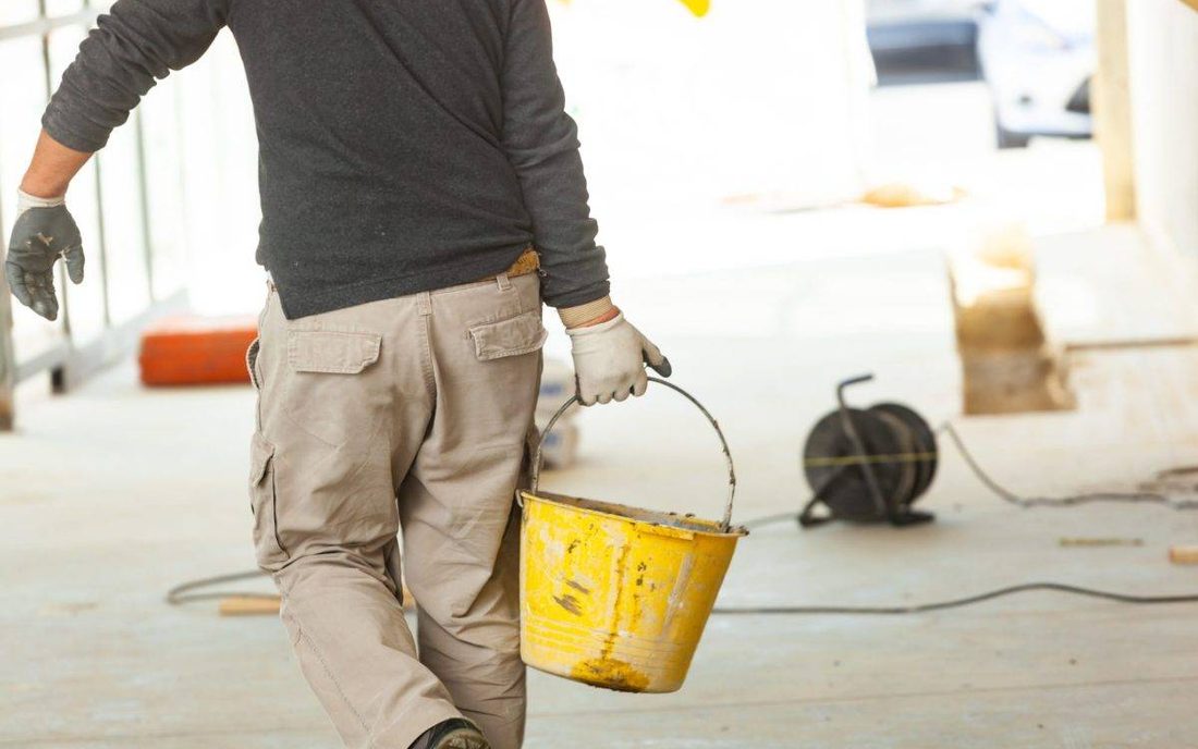 Trabajador de obra cargando una cubeta de mezcla